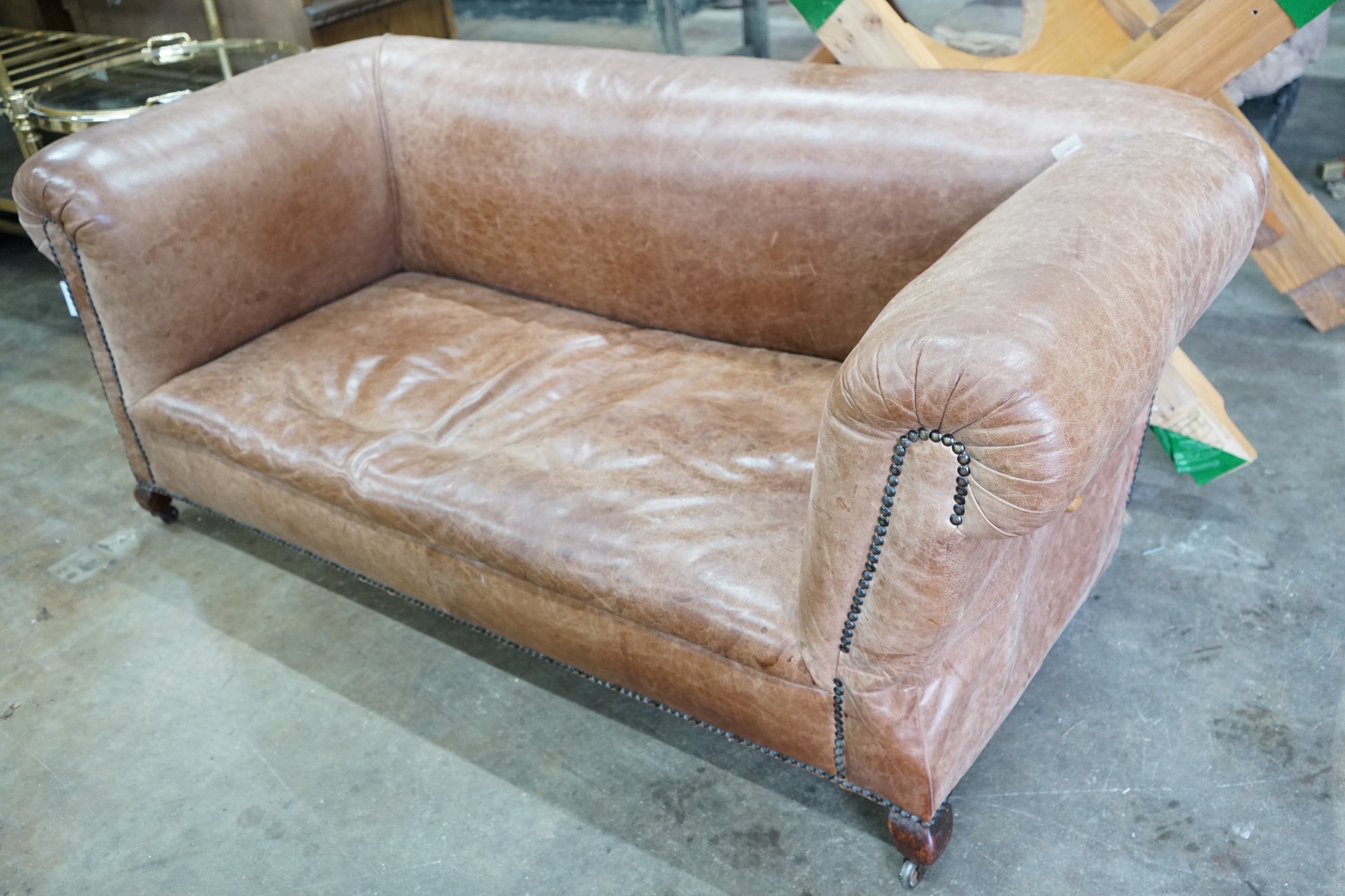 An early 20th century tan leather drop arm Chesterfield settee, width 160cms, depth 84cms, height 69cms.